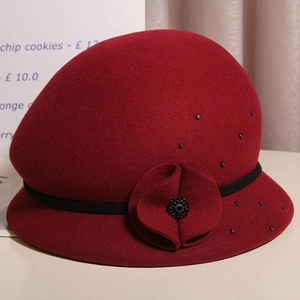 Dettaglio cappello in feltro di lana bordeaux con fiore e perline decorative