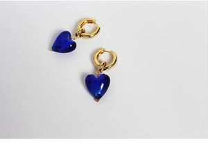 Macro shot of blue Murano style glass heart pendants with golden hoop earrings