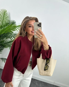 Close-up of a burgundy zip-up bomber jacket featuring a ribbed collar and soft texture