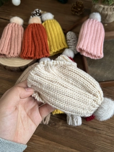 Detailed close-up of mini knitted Christmas hats with plush pom-poms for DIY crafts