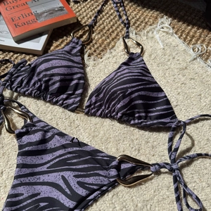 Detail view of purple zebra bikini with golden teardrop metal rings and side tie closures