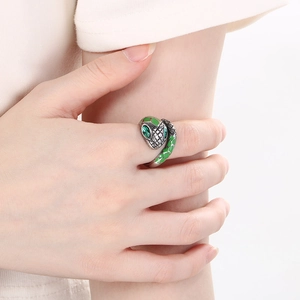 Close-up of luxury stainless steel snake ring with green emerald eyes on hand
