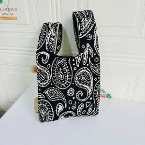Detailed knit tote bag featuring black and white paisley patterns with wide strap design