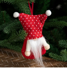 Detail of red polka dot Christmas gnome ornament hanging on lush green pine tree branches