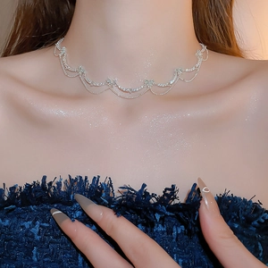Macro detail of silver-toned zircon butterfly heart necklace on model neck
