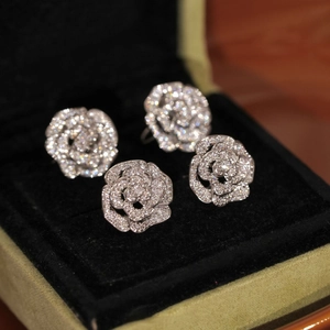 Gros plan de boucles d'oreilles camélia en argent pavées de diamants en écrin velours