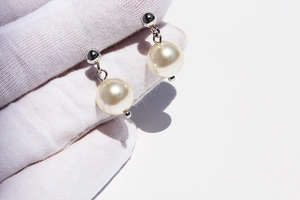 Close-up of elegant pearl drop earrings with silver finish and cream white round pearls