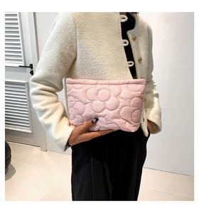 Detail of a pink floral quilted cosmetic bag held by a model for travel storage