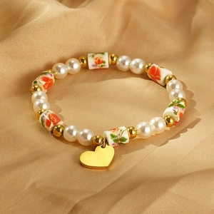 Détail du bracelet coeur avec perles et motifs floraux sur satin doré