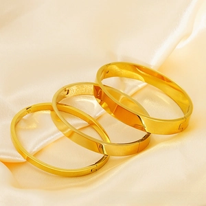 Macro shot of three polished 18K gold-plated stainless steel oval bangle bracelets