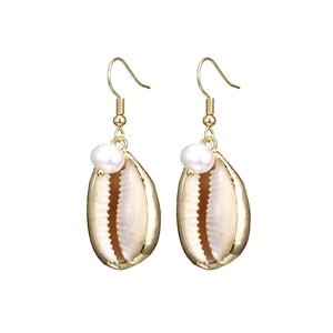 Detailed view of golden seashell earrings with natural shells and white pearls