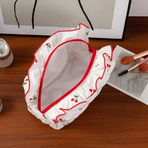 Détail de la trousse à maquillage cerise avec texture matelassée et bord à volants