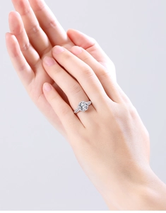 Close-up of a 2-carat Moissanite ring with a halo of small gems on a model hand