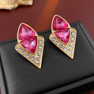 Nahaufnahme der goldenen Ohrstecker mit rosa Dreiecksteinen und kleinen weißen Steinen