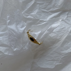 Detailed view of a gold 925 silver ring featuring a black evil eye inlay on wrinkled paper