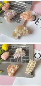 Detail of floral hair claws in marble pink and purple on a white laptop background