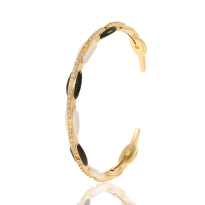 Detail of gold-plated bangle with black and white enamel inlays and micro-set cubic zirconia
