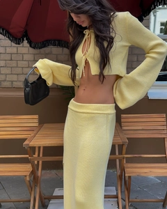 Détail du haut en tricot jaune clair à nouer et texture de la jupe ajustée