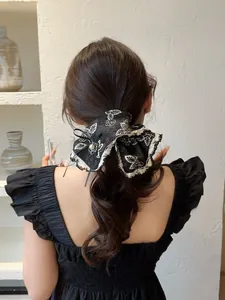 Detailed shot of black lace hair scrunchie with white flower embroidery and pearl