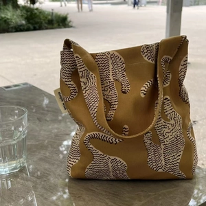 Gros plan de l'imprimé tigre sur le sac fourre-tout en coton jaune moutarde avec étiquette