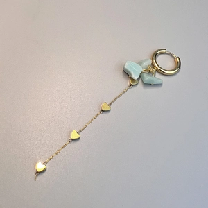 Detail of bohemian gold earrings with heart charms and natural light green stones