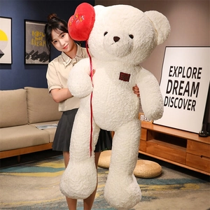 Giant white teddy bear plush with red heart balloon decoration in cozy home setting