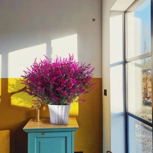 Lush artificial purple lavender in a white ribbed pot placed by a sunny window