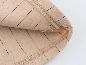 Gros plan sur un tissu beige à rayures montrant les coutures et les détails de texture