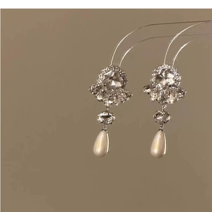 Detailed view of silver flower earrings with rhinestones and teardrop pearl drops