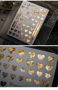 Macro detail of EM-013 golden heart nail stickers with metallic foil texture
