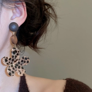 Close-up of leopard print flower drop earrings on a model with elegant brown tones