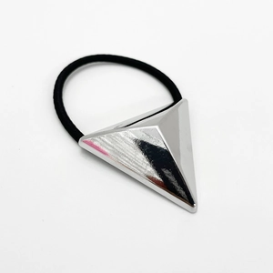 Macro shot of silver pyramid charm on black elastic hair tie with polished metal finish