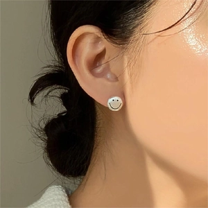 Close-up of minimalist sterling silver smiley face stud earrings worn by a model
