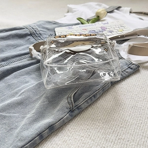Close-up of clear PVC capybara crossbody bag with adjustable strap on denim background