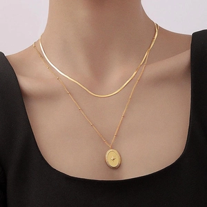 Double-layered gold necklace featuring a flat snake chain and oval starburst pendant