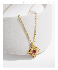 Detail of vintage square gold necklace with red gemstone on stone arch stand