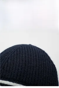 Détail de la maille côtelée bleu marine et des rayures blanches sur ce bonnet d'hiver