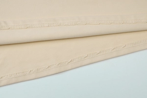 Detailed close-up showing reinforced double stitching on beige knitted dress hemline
