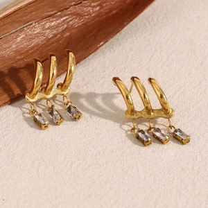 Detail of 18K gold plated earrings with triple rectangle zircon tassels on rustic wood