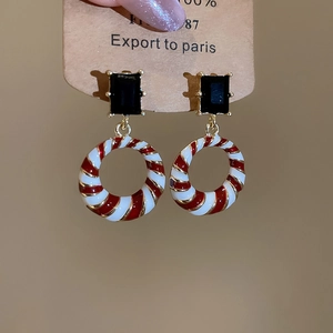 Detail of geometric round drop earrings with red and white stripes and black gems