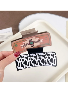 Detail of western style hair claws with cow print and geometric leather patterns