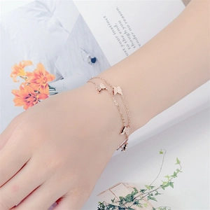 Elegant butterfly charm bracelet in rose gold stainless steel worn by a female model