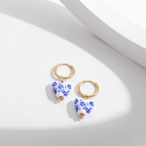 Detail of heart-shaped blue and white porcelain earrings with gold stainless steel hoops