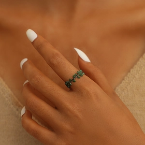 Close-up of a green enamel leaf open ring on a finger with a nature-inspired design
