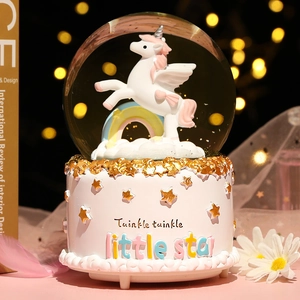Detailed close-up of a unicorn snow globe music box with a pink cake-shaped base