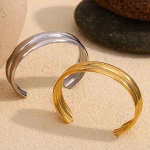 Dettaglio di bracciali a doppio strato in oro e argento su pietre naturali