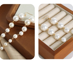 Detail of vintage style faux pearl tassel earrings displayed in a wooden jewelry box