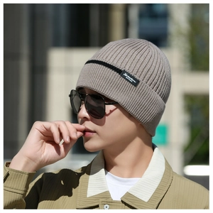 Detail of knitted beanie showing Narasan fashion label and fine texture on grey fabric