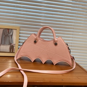 Detail of pink PU leather bat-shaped bag with spiderweb quilting and metal cross hardware