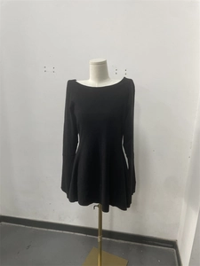 Detail view of a black long-sleeve knit peplum dress with a wide neckline on a mannequin
